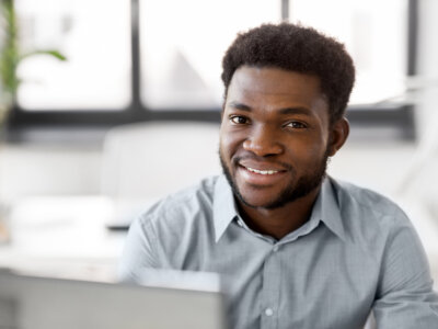 business, people and technology concept - african american businessman with laptop working computer at office